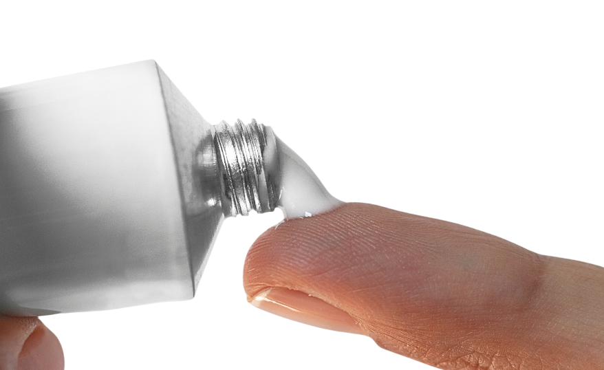 white tube of ointment being squeezed on a finger